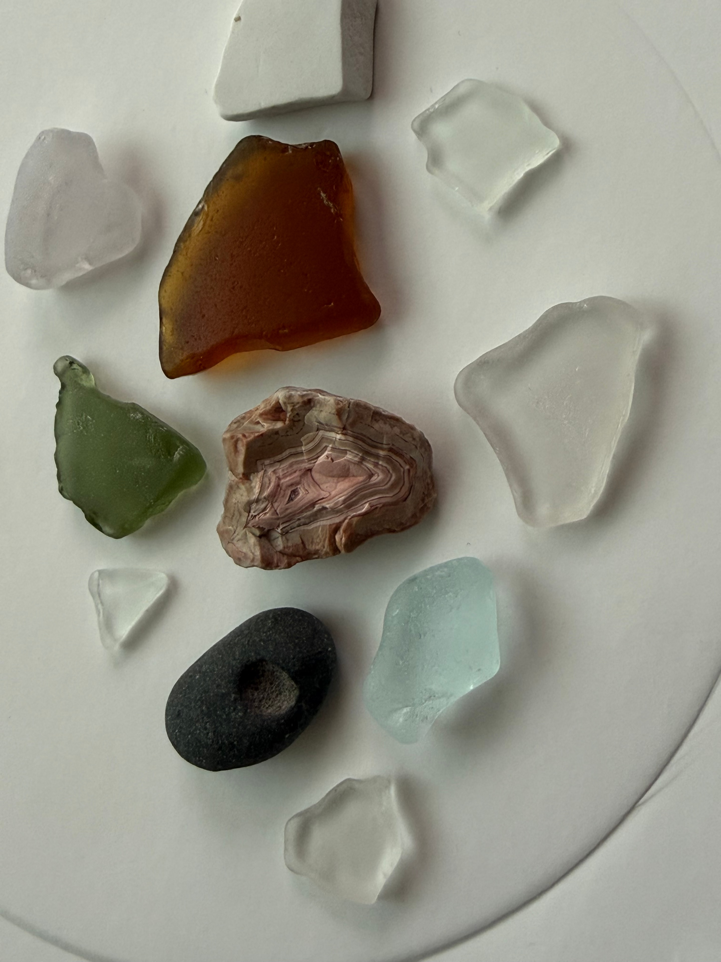Beach glass, agate, and jasper finds on a white plate